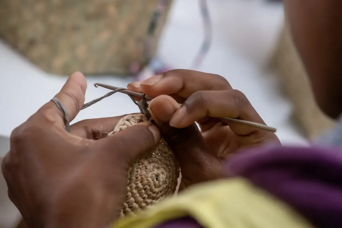Gros plan sur les mains d'une artisane SOBIKA travaillant le crochet raphia